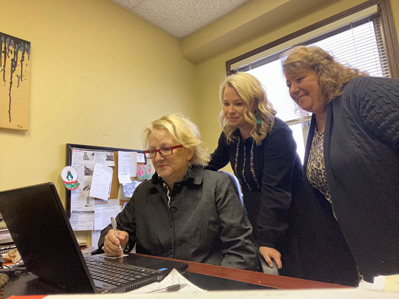 Staff members gathered around a laptop