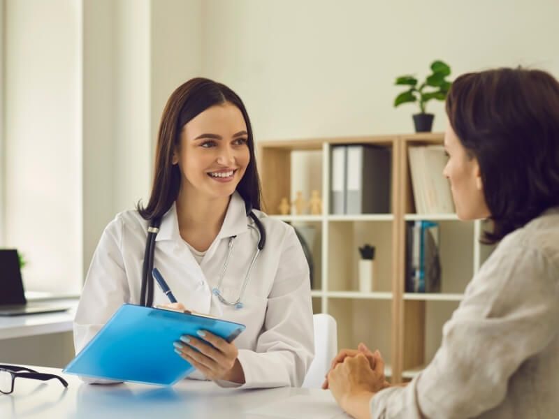 Smiling female doctor talking to a female patient in a private office