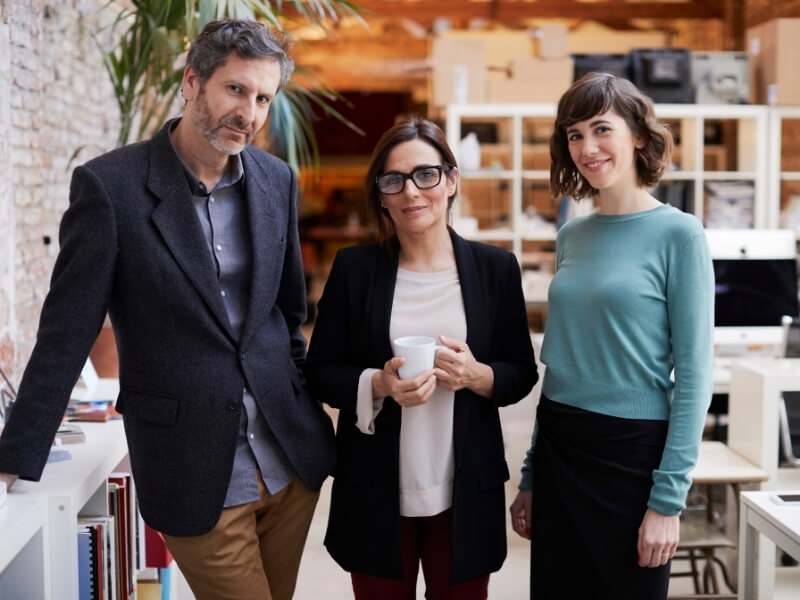 Three employees standing in a modern office space